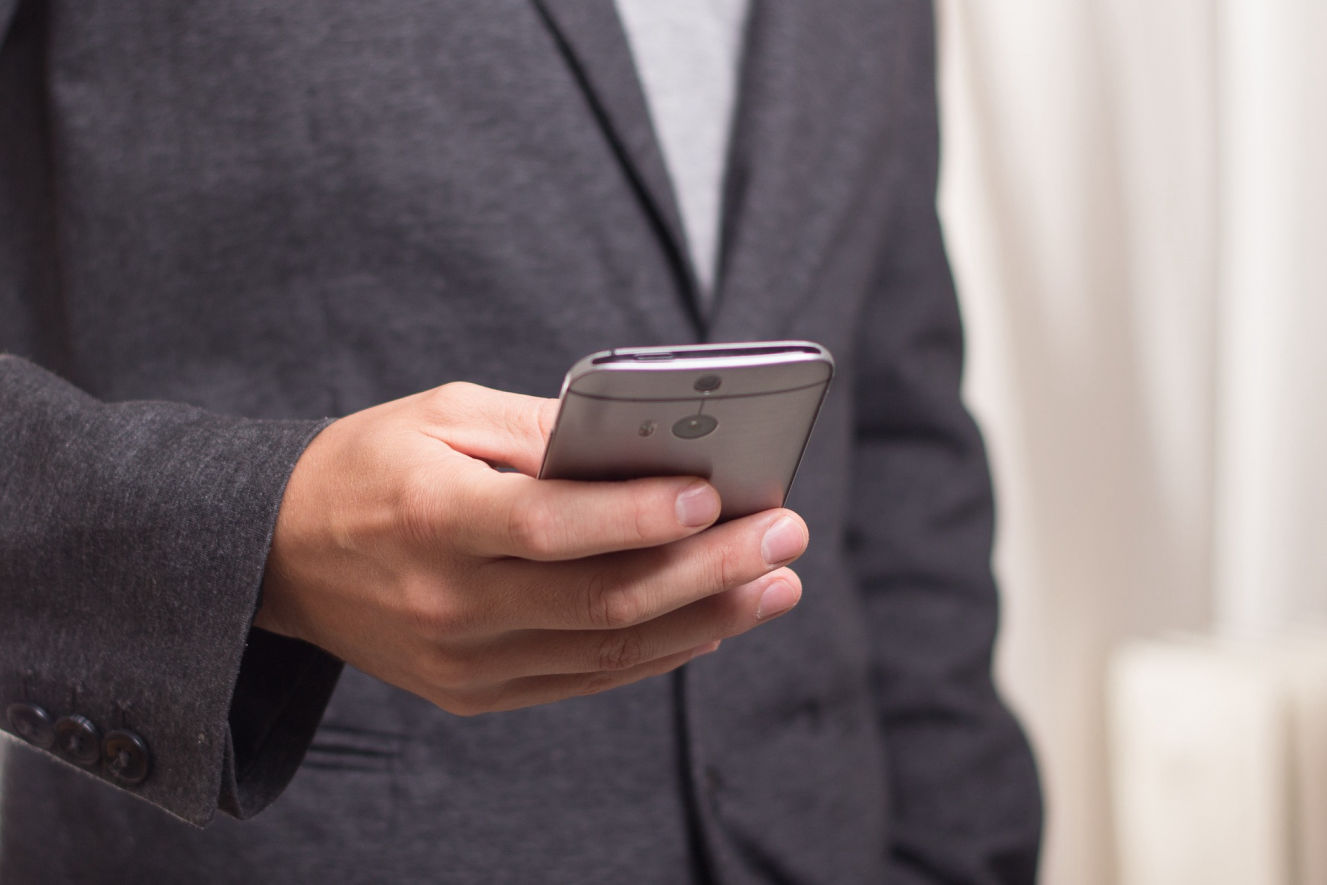 Jemand hält ein Mobiltelefon in der Hand